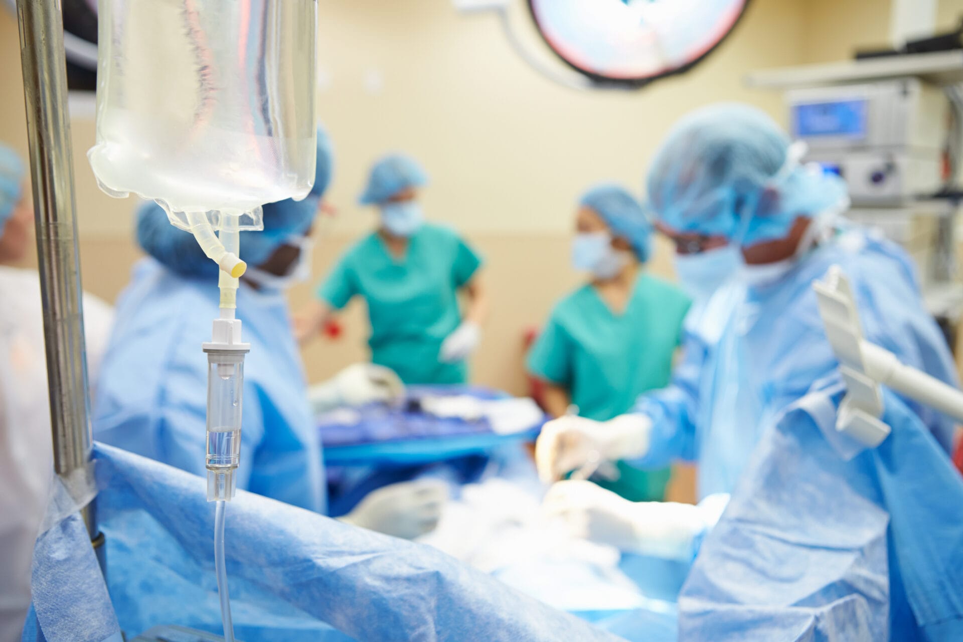 Surgical Team Working In Operating Theatre Wearing Protective Clothing